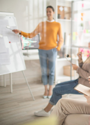 Eine verschwommene Ansicht einer Frau, die mit einem Stift auf ein Flipchart zeigt.