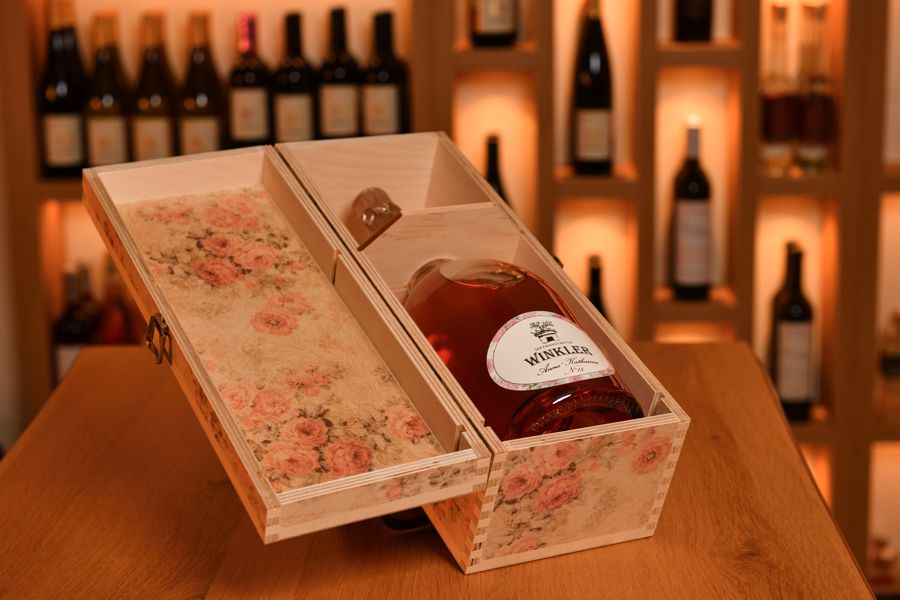 Ausstellung einer Getränkeflasche in einer floralen Holzkiste.