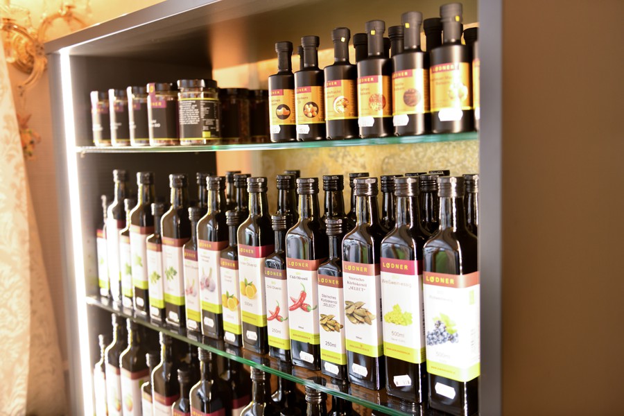 Regal mit einer Vielzahl an Flaschen mit Ölen und Essigen, ordentlich und übersichtlich sortiert.