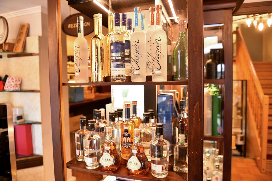 Verkaufsregal mit edlen Spirituosen und Feinkostflaschen in einem stilvollen Innenbereich mit Holzelementen.