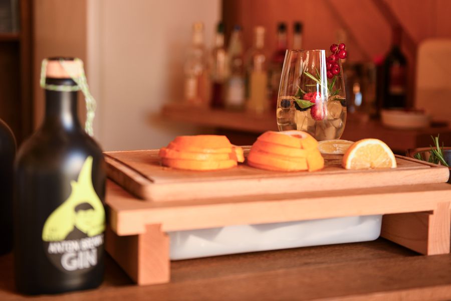 Holzbrett mit geschnittenen Orangen und einem Glas mit Beeren dekoriert.