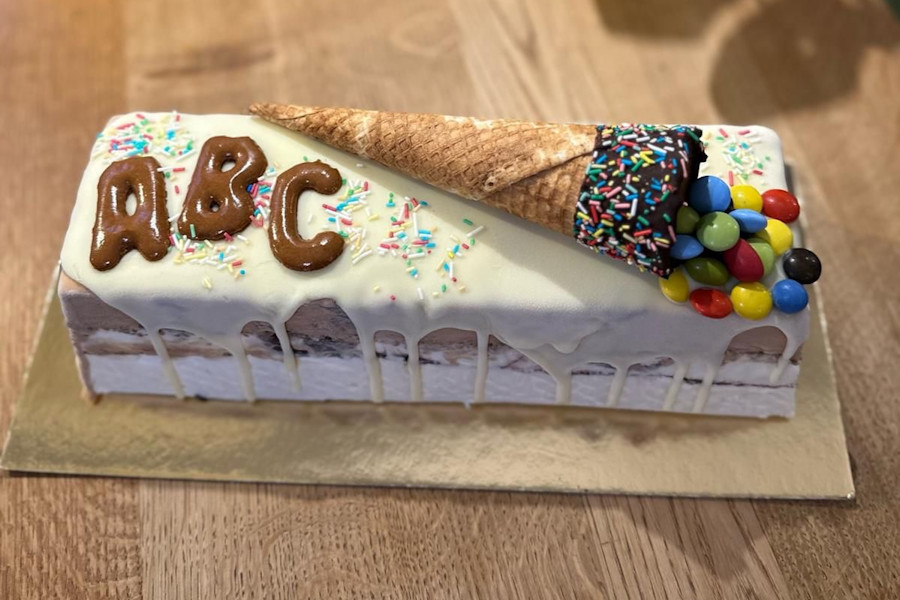 Eine kastenförmige Eistorte zum Schulstart mit ABC und einer Waffel als Schultüte mit Schokolinsen.