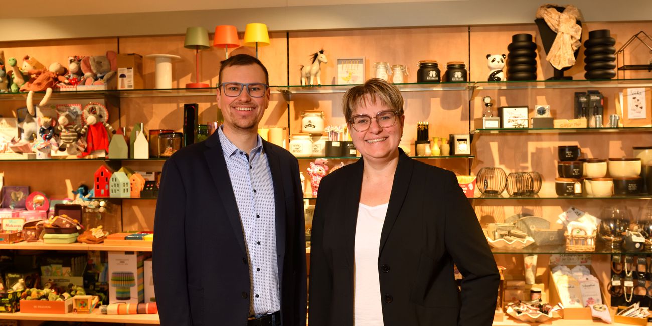 Philipp Hutter und Private Banking Beraterin Martina Walburger stehen vor einer Sortimentsauswahl im Ladengeschäft.