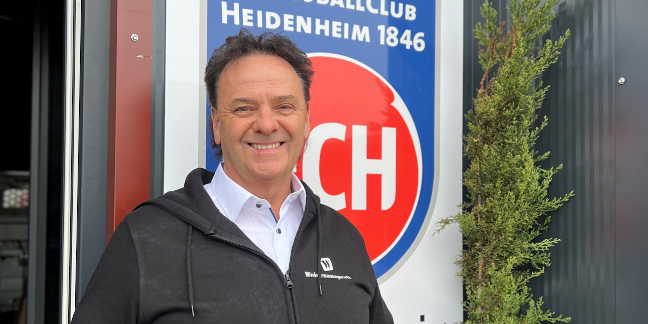 Ralf Renner vor dem Logo des Fußballclub Heidenheim 1846