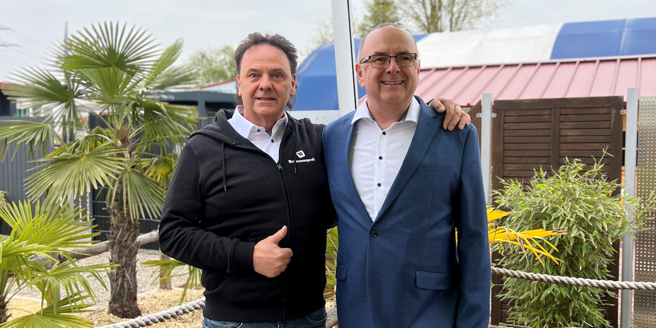 Ralf Renner und Private Banking Berater Alwin Renner halten sich partnerschaftlich an der Schulter mit Daumen hoch.