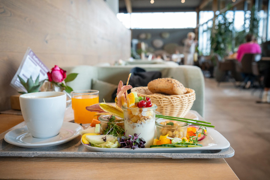 Angerichteter Frühstücksteller mit Tasse, Saft und verschiedenen Lebensmitteln.