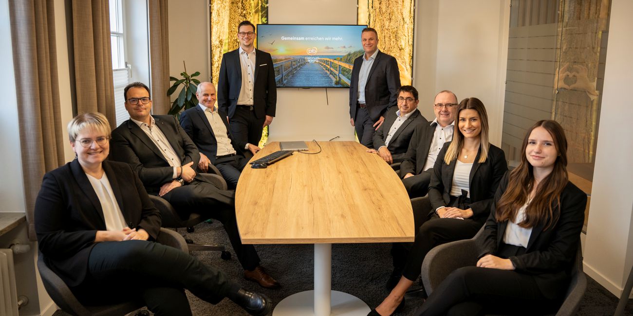 Das komplette Team Platinum Banking sitzt an einem Tisch und lächelt in die Kamera.